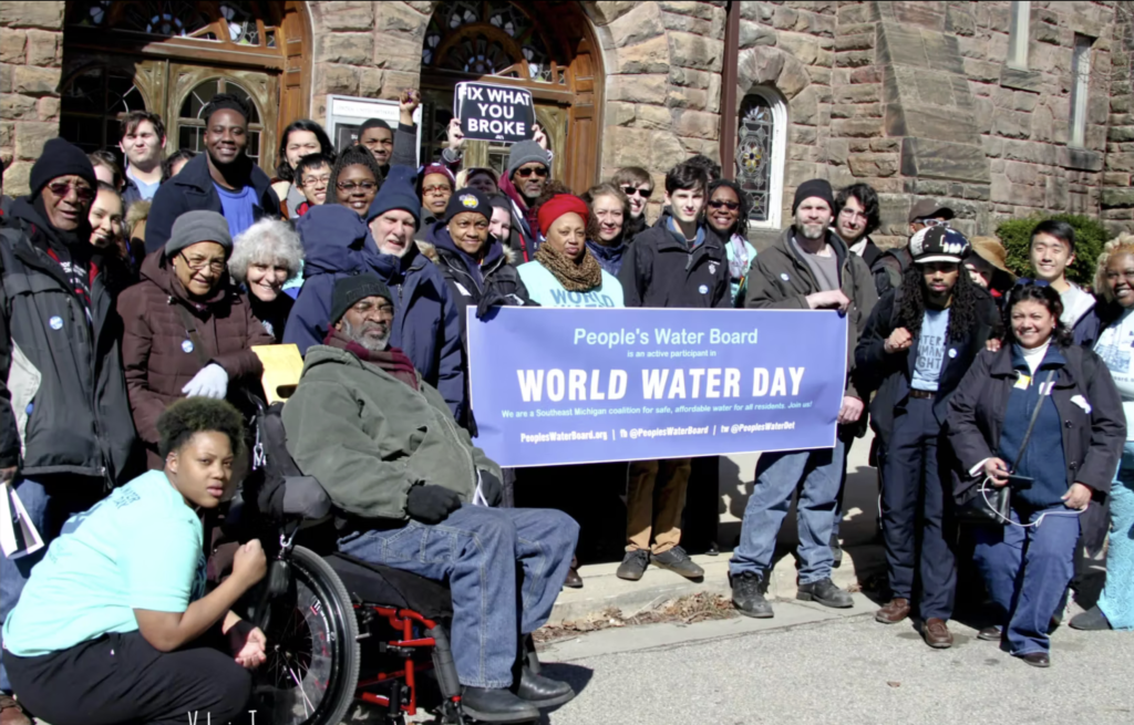 A group of protesters stands outside with signs calling for water rights on World Water Day.